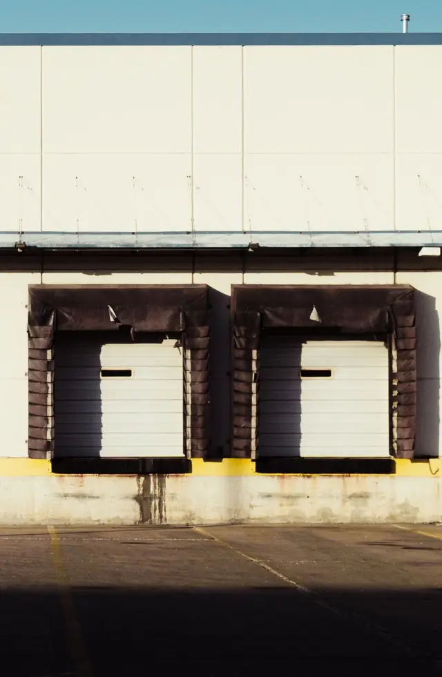 Two closed loading dock doors on a warehouse wall in late sunlight
